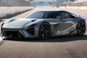 현대적이고 공기역학적인 디자인의 세련된 은색 렉서스 스포츠카가 매끄러운 표면에서 빛을 반사하며 레이싱 트랙에 주차되어 있습니다. 트랙과 텅 빈 관중석이 배경으로 보입니다.